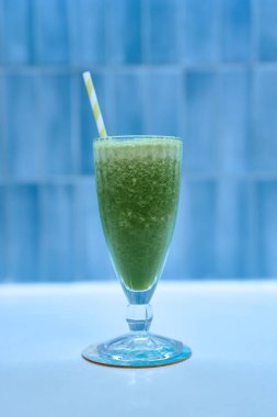 Zarif bardakta servis edilen yeşil smoothie şeritli saman, sağlıklı yaşam tarzı ve yaz titreşimleri için mükemmel.