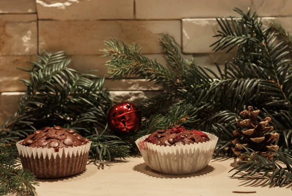 Kağıt, kırmızı bir Noel çan, bir çam kozalağı ve bazı yeşil Çamın dalları iki çikolata cupcakes