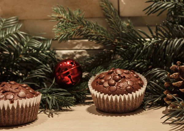 İki çikolatalı kek kağıt, kırmızı bir Noel çan, bir çam kozalağı ve bazı yeşil Çamın dalları