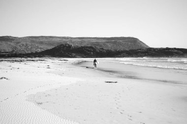 Güney Afrika, Cape Town, siyah-beyaz fotoğraf plaj boyunca mesafe yürüyen bir sörf tahtası ile bir sörfçü