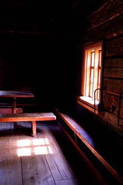 Helsinki 'de eski ahşap bir binanın içi. Pencereden, masadan ve koltuklardan ışık geliyor.