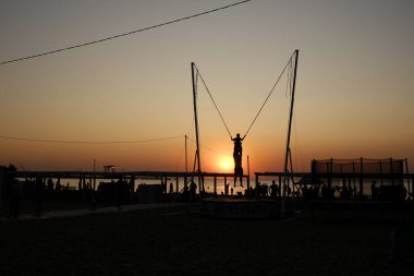 Rusya 'nın Anapa kentindeki Karadeniz' de gün batımında iplerle trambolin atlamak. 