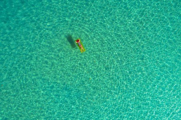 セーシェルの透明なターコイズ ブルーの海で泳ぐマットレスの上スイミングにスリムな女性の空撮 夏の女の子 波が美しい カラフルな水と海の風景 ドローンから平面図 — ストック写真