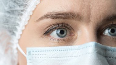 Bir doktor yaygın olarak açılan gözlerini kapatın. Koruyucu maske güzel gözlü kadın doktor yakın çekim. 