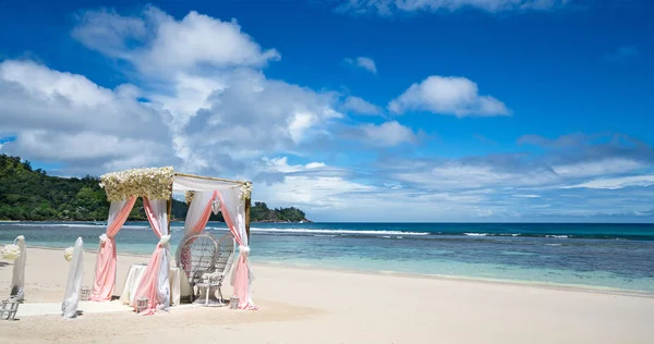 Wedding arch decorated with flowers on a tropical sand beach. Outdoor beach wedding setup. Wedding arch and set up on beach Seychelles