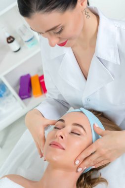 Sağlık merkezinde hastası olan bir kadın güzellik uzmanı var. Profesyonel kozmetolog kozmetoloji kabinesinde ya da güzellik salonunda güzel bir kıza prosedür uygular..