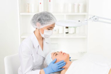 Sağlık merkezinde hastası olan bir kadın güzellik uzmanı var. Profesyonel kozmetolog kozmetoloji kabinesinde ya da güzellik salonunda güzel bir kıza prosedür uygular..