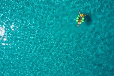 İnce kadın yüzme yüzmek halka çörek de Seyşeller şeffaf turkuaz denizin üzerinde hava görünümünü. Yaz deniz kızı, güzel dalgalar, renkli su ile. Drone üzerinden üstten görünüm