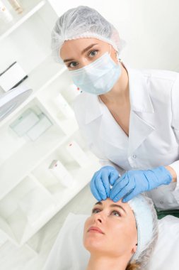 Sağlık merkezinde hastası olan bir kadın güzellik uzmanı var. Profesyonel kozmetolog kozmetoloji kabinesinde ya da güzellik salonunda güzel bir kıza prosedür uygular..