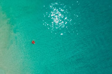 İnce kadın yüzme yüzmek halka çörek de Seyşeller şeffaf turkuaz denizin üzerinde hava görünümünü. Yaz deniz kızı, güzel dalgalar, renkli su ile. Drone üzerinden üstten görünüm