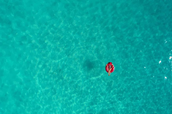 Luftaufnahme einer schlanken Frau, die auf dem Schwimmring im Wasser schwimmt — Stockfoto