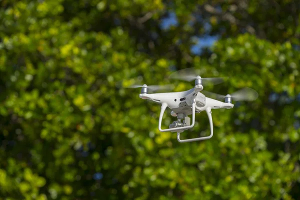 Drone en vol, arbres verts en arrière-plan, mise au point sélective — Photo