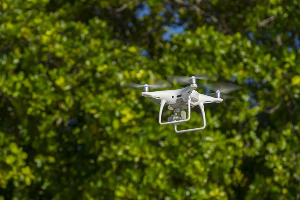 Drone en vol, arbres verts en arrière-plan, mise au point sélective — Photo