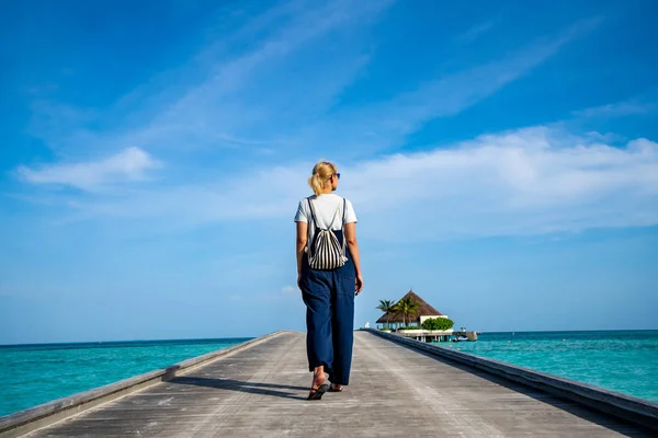 Mujer feliz caminando por el muelle de madera con mar azul y cielo — Foto de Stock