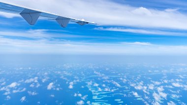 Mavi bulutların üzerinde uçan uçak kanadı.