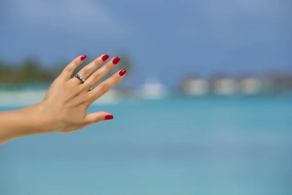 Крупним планом жіночий палець, що показує заручини кільце на тропічному — стокове фото