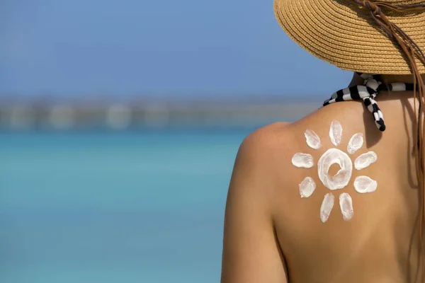 Frau mit sonnenförmiger Sonnencreme am Strand — Stockfoto