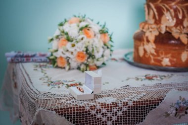 Altın alyans kutusu ve çiçek buket masanın üzerinde bir kaç