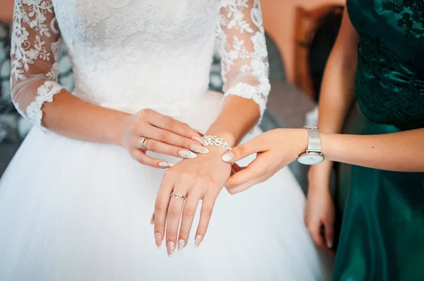 Demoiselle d'honneur aide à porter le bracelet sur la main des mariées — Photo