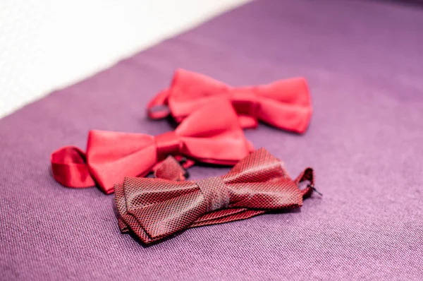 Red bow ties lying on the purple background