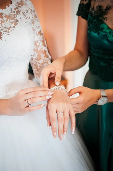 Bridesmaid helps to wear bracelet on the brides hand