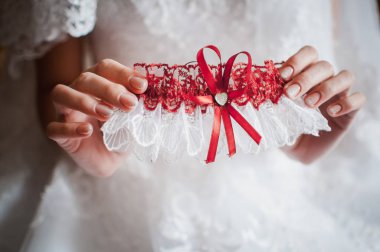 Gelin elinde kırmızı ve beyaz jartiyer tutan