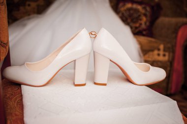 Beyaz bir ayakkabı çifti arasında altın alyans çifti