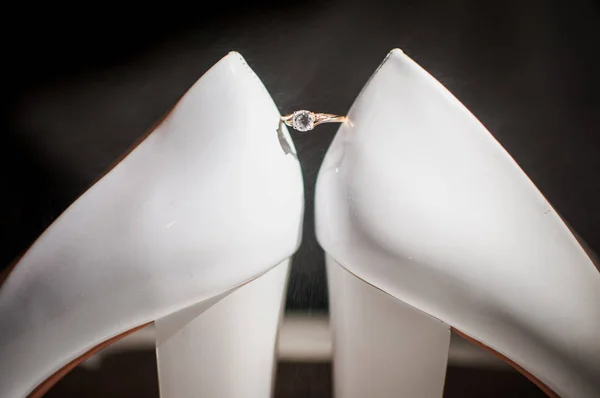 Gyllene ring med diamant mellan ett par vita skor — Stockfoto