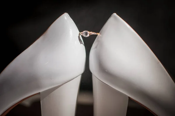 Anillo de oro con diamante entre un par de zapatos blancos — Foto de Stock