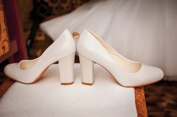 Dvojice zlatých svatebních prstenců mezi dvěma bílými botami — Stock fotografie