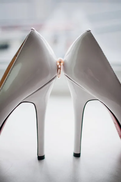 Zlatý prsten s perlou mezi dvěma bílými botami — Stock fotografie