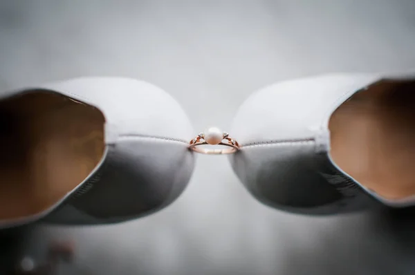 Gouden ring met parel tussen paar witte schoenen — Stockfoto