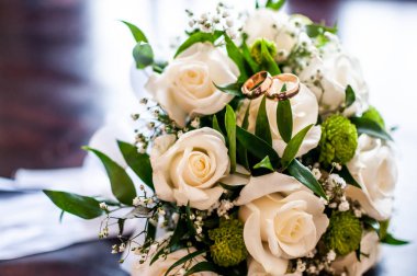 Üzerinde altın alyanslar olan gül buketi