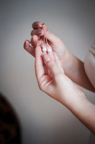 Pendientes con perlas blancas en la mano de la novia — Foto de Stock