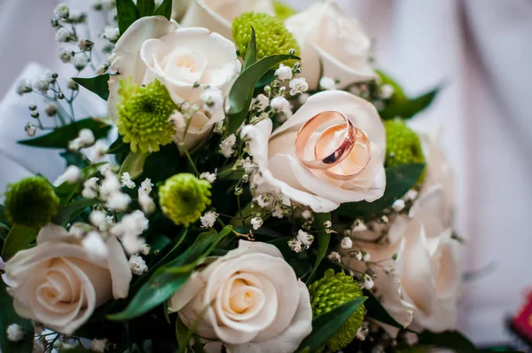 Bukiet róż ze złotymi pierścieniami ślubnych na nim — Zdjęcie stockowe