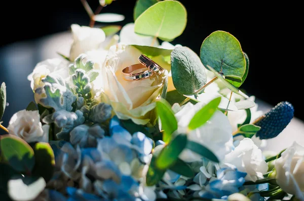 Золотые обручальные кольца на розовом букете цветов — стоковое фото