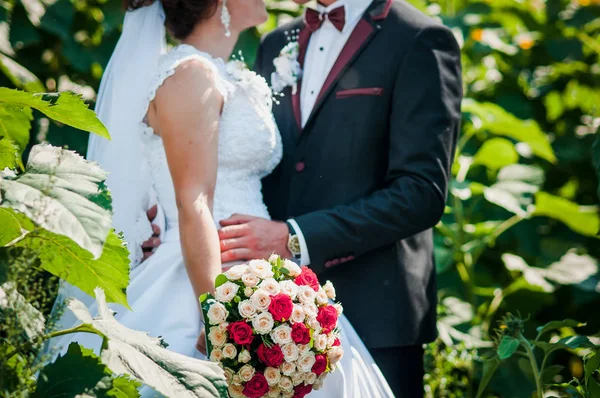 Bräutigam und Braut mit buntem Brautstrauß in der Hand — Stockfoto