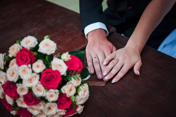 Sposa e sposo mani con mazzo di fiori sul tavolo — Foto Stock