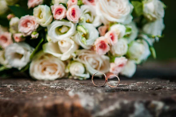 Cincin pernikahan emas pada karangan bunga merah muda — Stok Foto