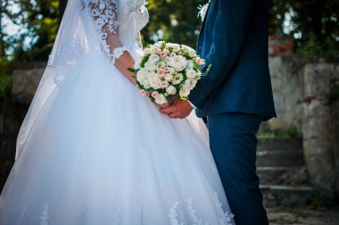 Damat ve gelin elinde renkli düğün buketi tutan