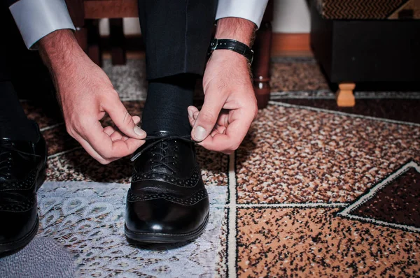 Blanke man zet zwarte schoenen op de witte achtergrond — Stockfoto