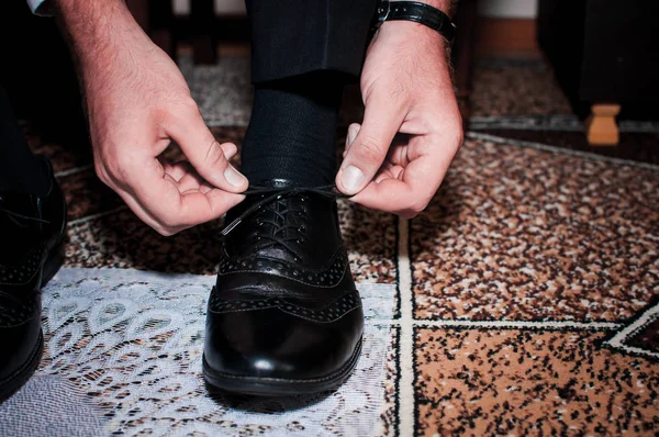 Blanke man zet zwarte schoenen op de witte achtergrond — Stockfoto