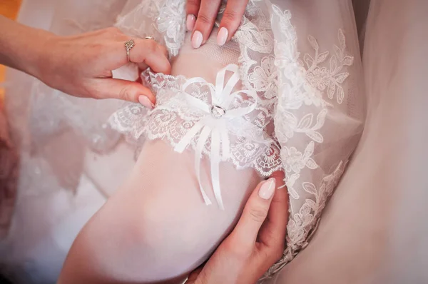 Koszorúslány ruházat fel fehér harisnyakötő a menyasszony lábát — Stock Fotó