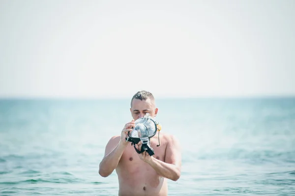 Man met zwem masker in de hand gaat op water — Stockfoto