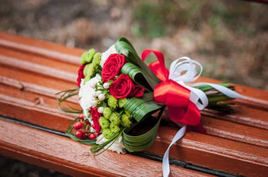 Beyaz çiçek buketi ile Kırmızı bir bankta yatıyor