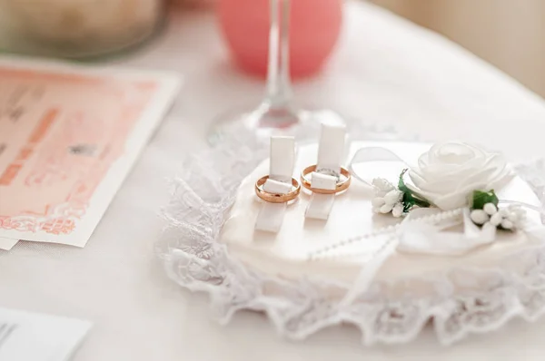 Zlaté snubní prsteny na bílém růžovou pozadí — Stock fotografie