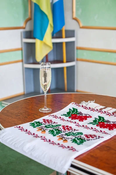 Бокал шампанского и вышитое полотенце стоят на столе — стоковое фото