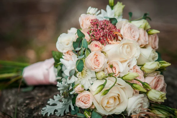 Χρυσά γαμήλια δαχτυλίδια σε μπουκέτο λουλούδια — Φωτογραφία Αρχείου