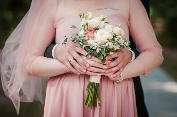 Groom and bride holding hands on the bouquet of flowers — Stock Photo, Image