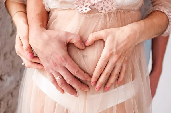 Hombre y mujer tomados de la mano en el vientre embarazada —  Fotos de Stock